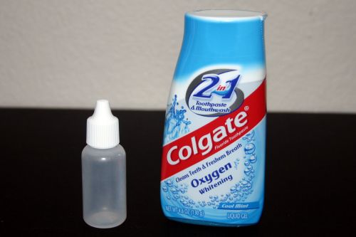 A regular bottle of Colgate toothpaste and an empty half-ounce eyedropper bottle.
